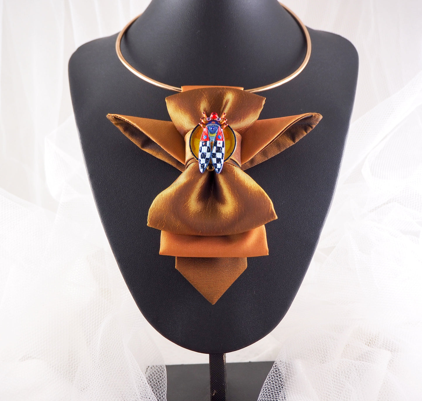 Brown bow-shaped necklace on a mannequin bust with a white lace background