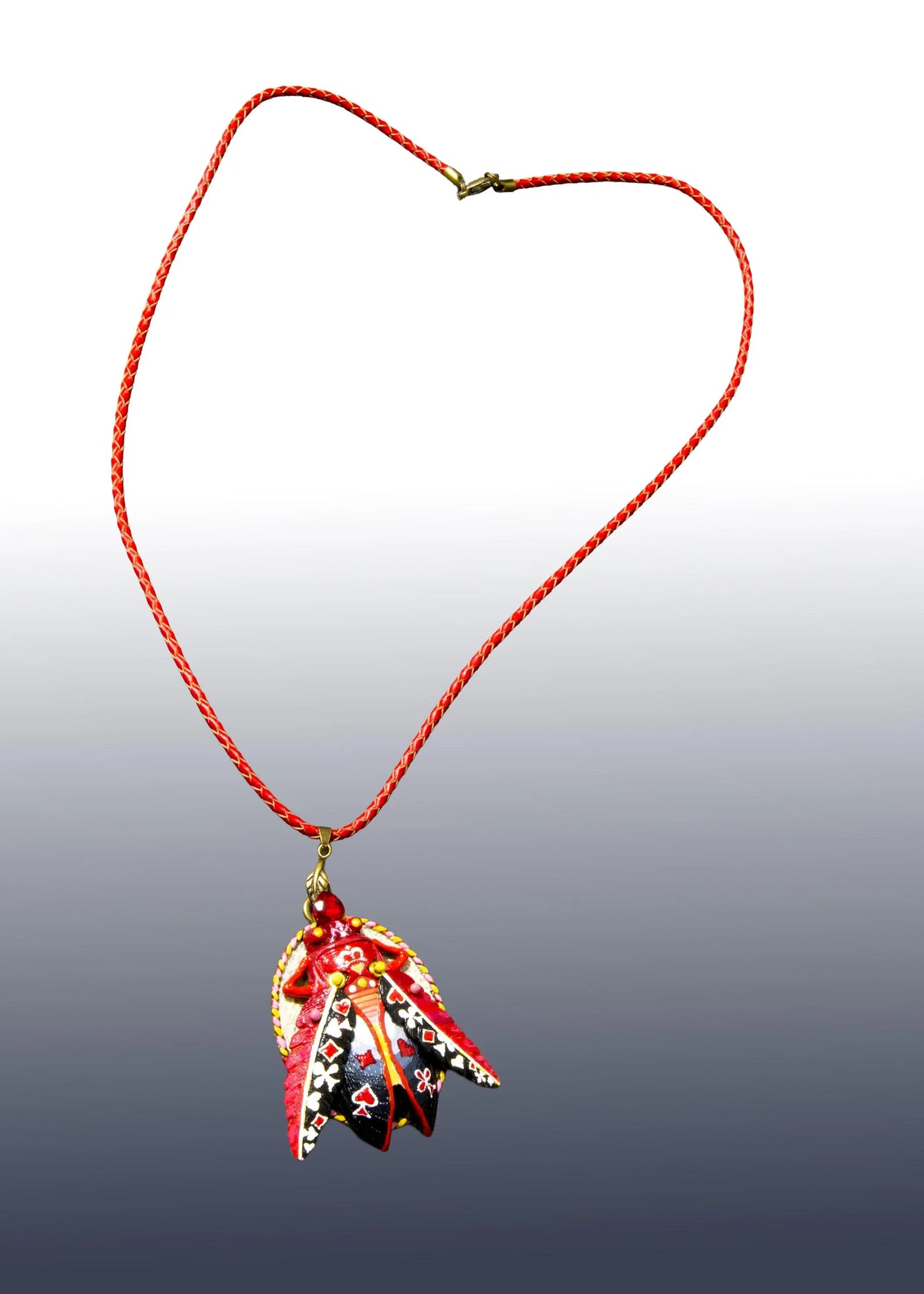 Necklace with a red cord and a decorative pendant on a gradient background