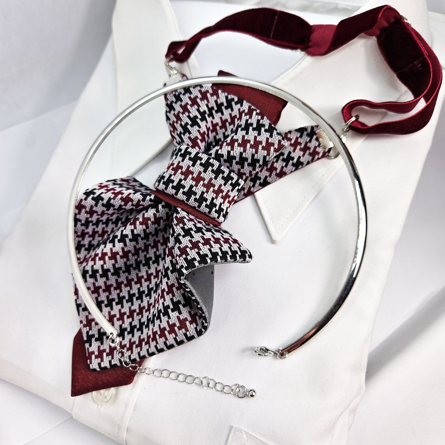 Houndstooth patterned bow tie with a silver ring on a white background