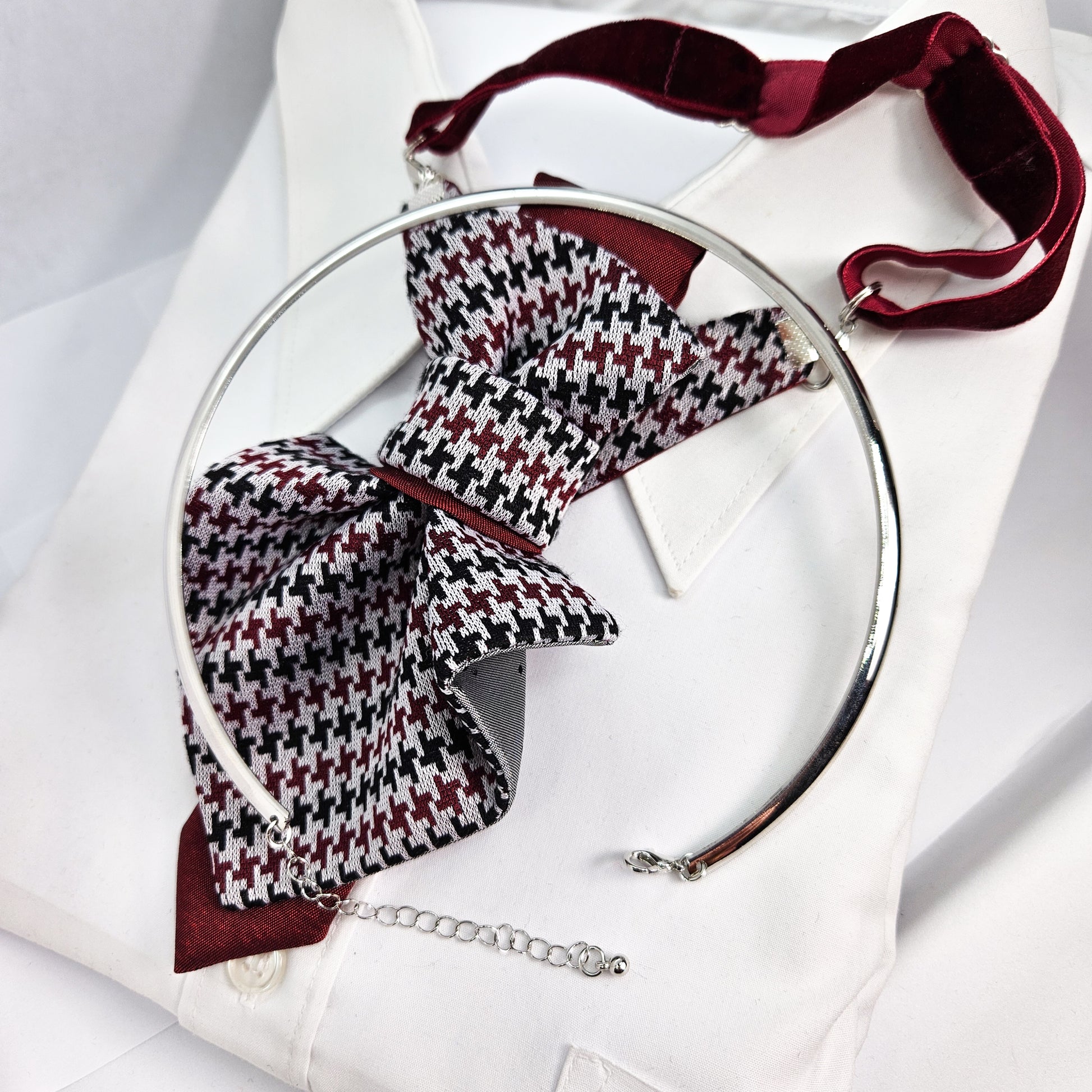 Houndstooth patterned bow tie with a silver ring on a white background