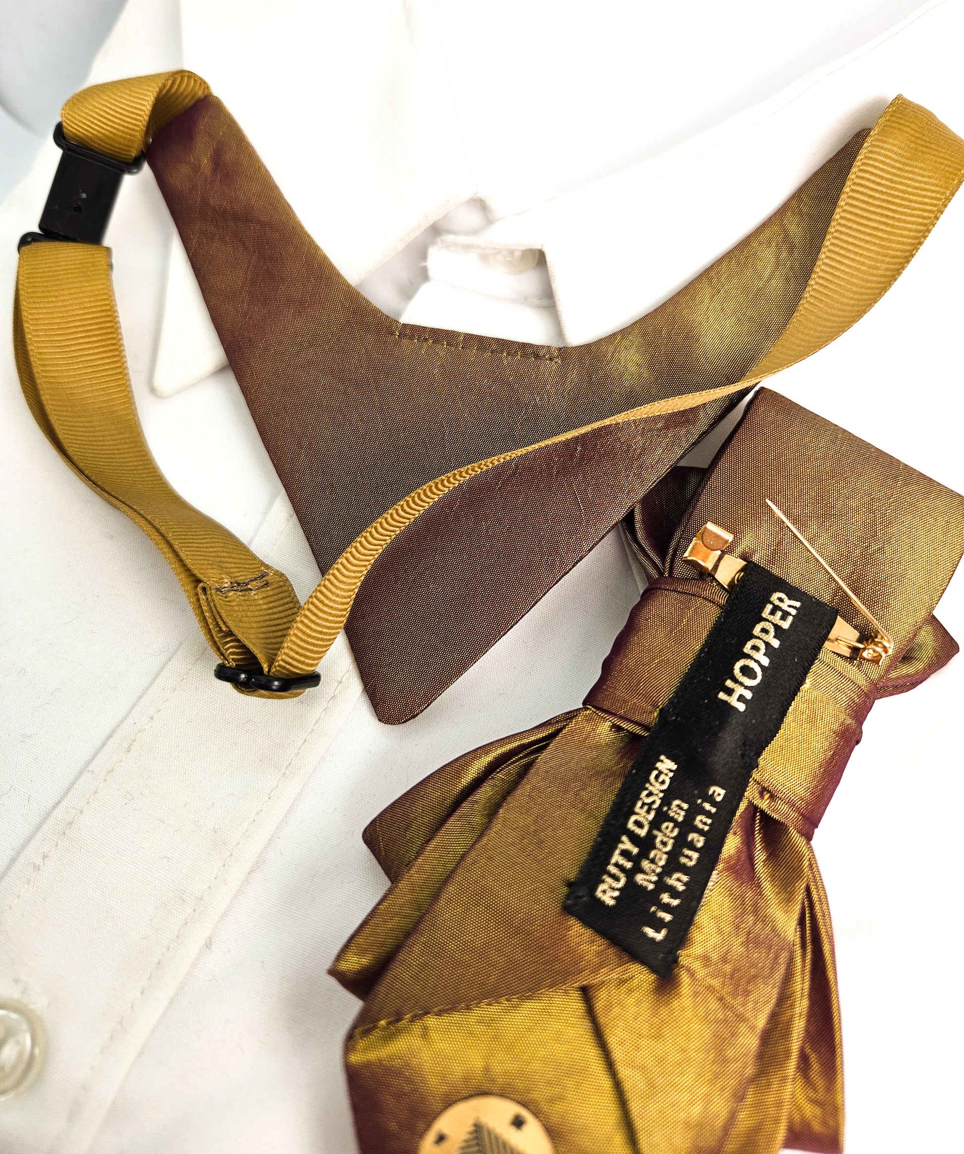 Brown leather vest with yellow suspenders and a visible brand tag on a white background metallic plum gold womens necktie, bronze burgundy metallic bow tie for women, chameleon fabric neck accessory, handmade statement necktie, sculptural womens neckwear, metallic plum bronze neckpiece, luxury handmade womens neck accessory, artistic fabric necktie, modern designer womens bow tie, elegant metallic neckwear, unique womens fashion necktie, gold burgundy neck accessory, contemporary statement neckpiece