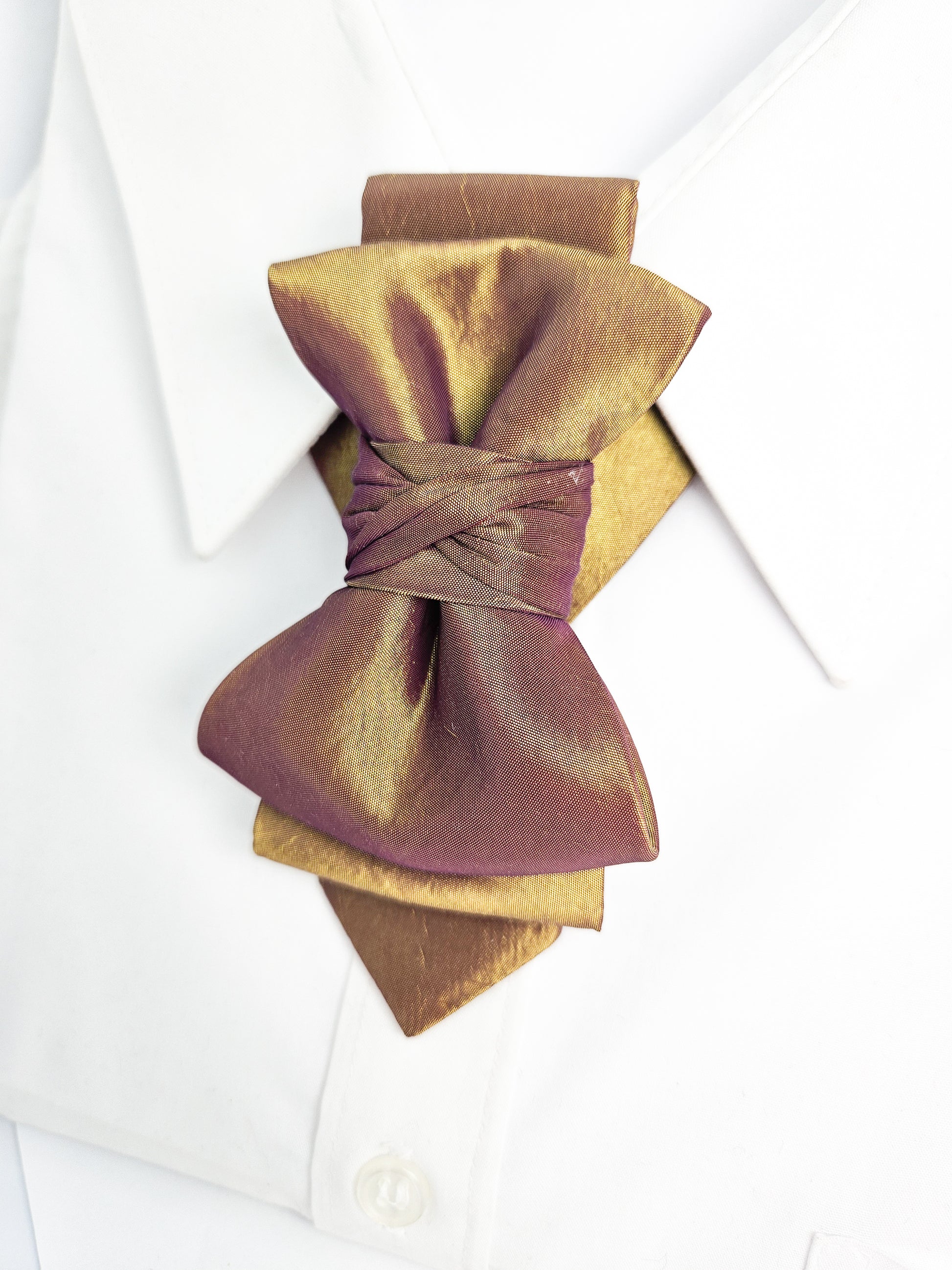 Gold and brown bow tie on a white shirt with a white background metallic plum gold womens necktie, bronze burgundy metallic bow tie for women, chameleon fabric neck accessory, handmade statement necktie, sculptural womens neckwear, metallic plum bronze neckpiece, luxury handmade womens neck accessory, artistic fabric necktie, modern designer womens bow tie, elegant metallic neckwear, unique womens fashion necktie, gold burgundy neck accessory, contemporary statement neckpiece