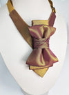 Gold and brown bow tie on a mannequin with a white background metallic plum gold womens necktie, bronze burgundy metallic bow tie for women, chameleon fabric neck accessory, handmade statement necktie, sculptural womens neckwear, metallic plum bronze neckpiece, luxury handmade womens neck accessory, artistic fabric necktie, modern designer womens bow tie, elegant metallic neckwear, unique womens fashion necktie, gold burgundy neck accessory, contemporary statement neckpiece