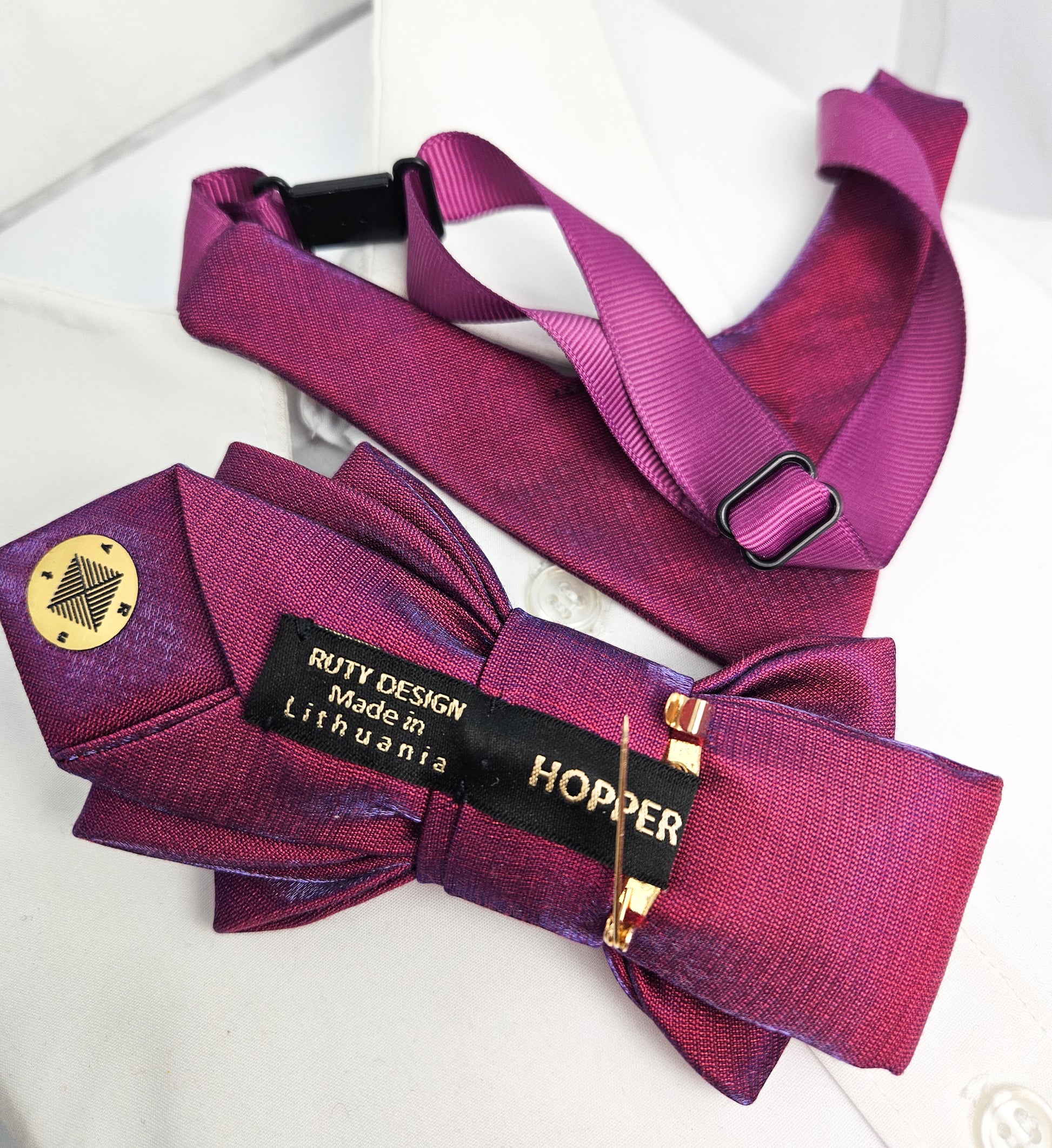 Purple bow tie with a visible brand label on a white background Handmade luxury fashion neck accessory, women's necktie accessory, purple satin necktie choker, gold choker with fabric tie, elegant women's neckwear, unique fashion accessory, stylish purple necktie for women, luxury handmade choker, modern neck accessory for women, fashionable women's tie necklace, chic and sophisticated neckpiece, bespoke fabric tie, artisan crafted neckwear, high-end ladies' accessory, formal women's tie, statement neck acc