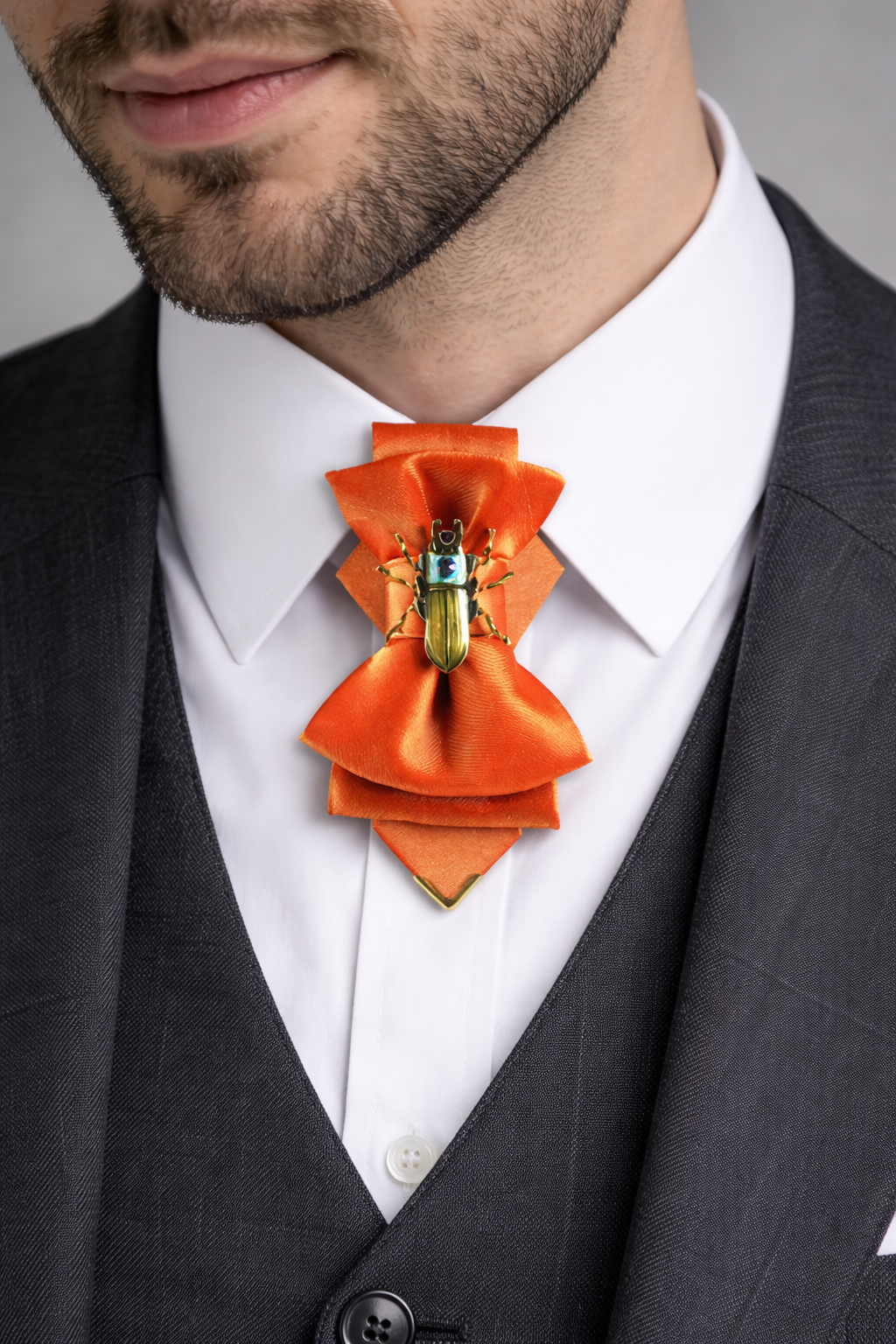 Man wearing a black suit with an orange bow tie featuring a green insect design.