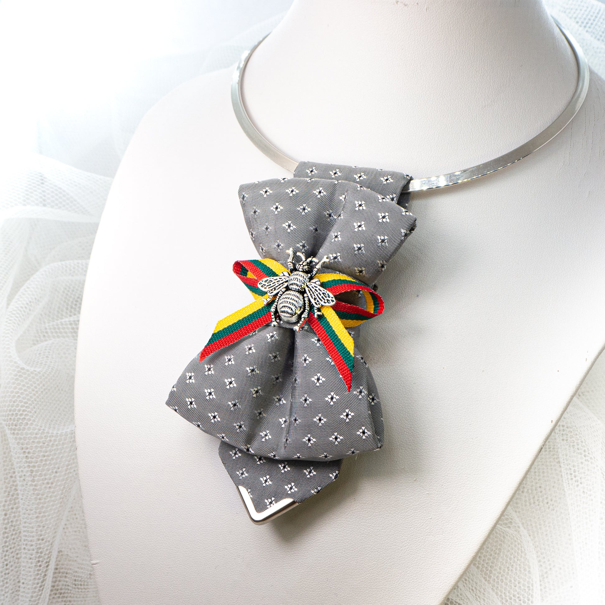 Bow tie "Bitute pilkoji" is a work, dedicated to the birthday of Vilnius, the capital of Lithuania.  Brass Vytis adorns the original knot of three fabrics. Keistas kaklaraištis, nematyta peteliškė, Vilniaus kaklaraištis, Kaklaraištis žiogas, keista varlytė