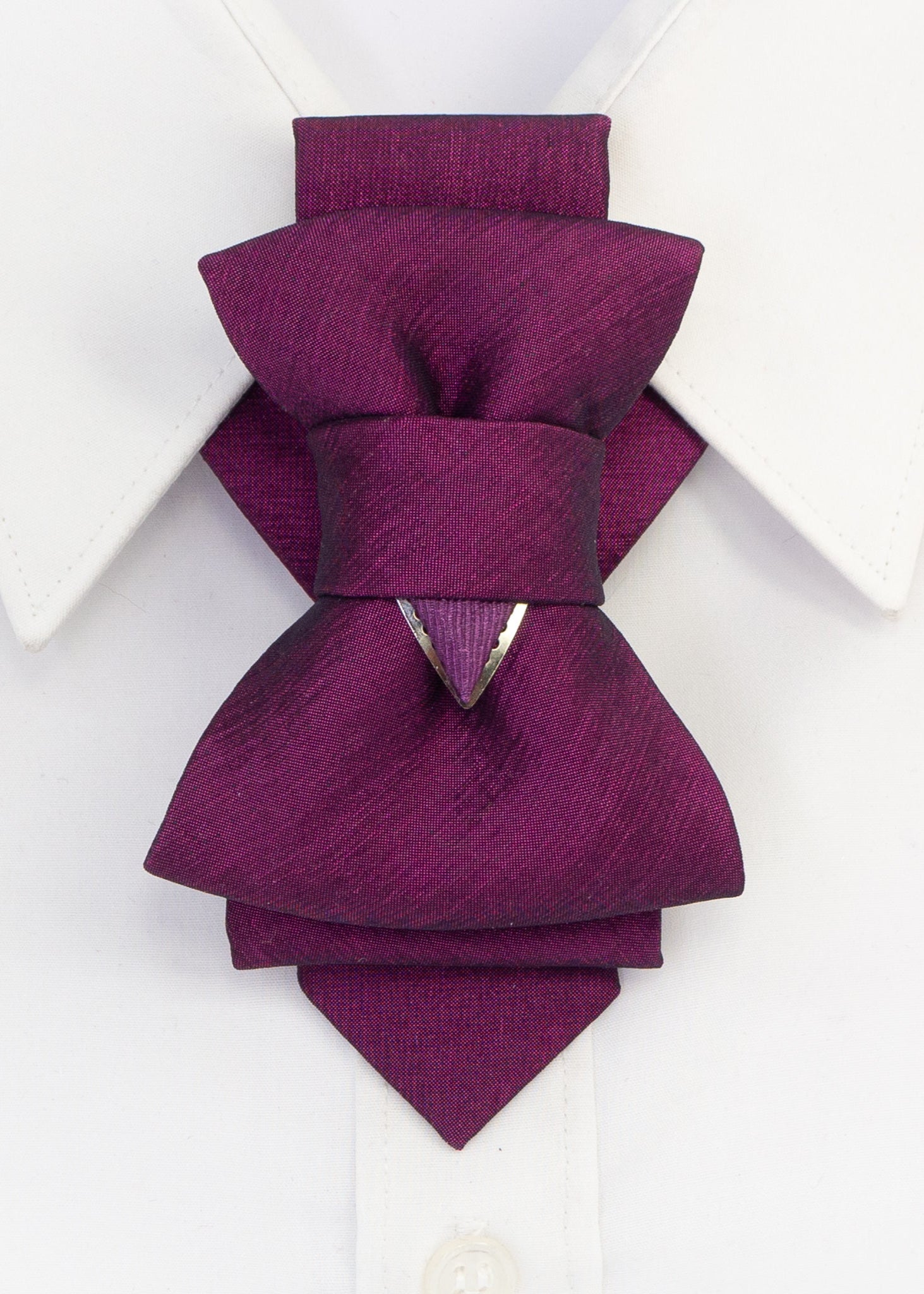 A pre-tied fabric bow tie in shades of pink and purple, displayed on a white shirt collar.