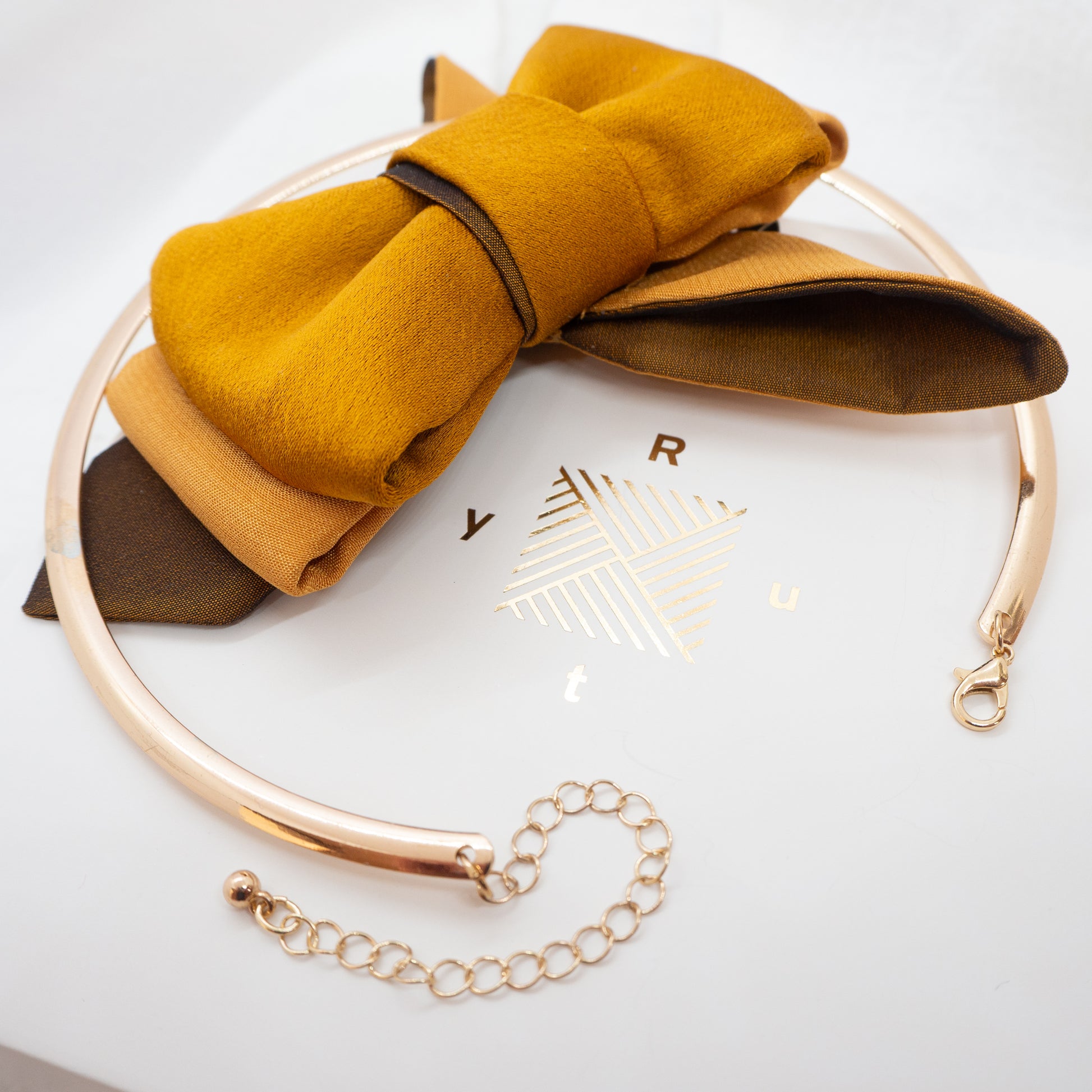 Gold headband with a mustard yellow bow on a white background handmade luxury neck accessory, women statement tie, vertical bow tie for women, gold satin necktie, elegant women tie, unique bow tie alternative, luxury handmade tie, artistic neckwear for women, modern formal accessory, gold statement necklace tie, designer women necktie, wedding guest accessory women, avant garde fashion tie, silk bow tie alternative, bold women fashion accessory, golden necktie women, formal outfit statement piece stylish of