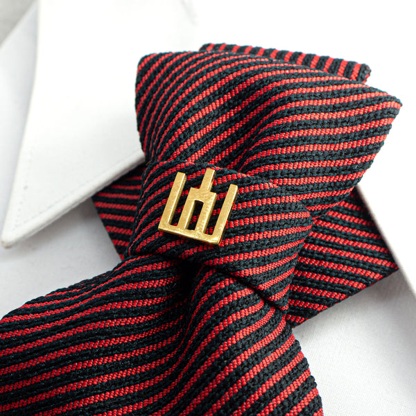 Black and red striped tie with a gold clasp on a white background red black striped jabot tie, gold Gedimino stulpai emblem, handmade heritage necktie, Lithuanian cultural fashion, artisan jabot-style tie, elegant striped tie gold badge, luxury heritage necktie, cultural fashion accessory, Lithuanian identity tie, formal jabot tie, handcrafted Lithuanian motif tie