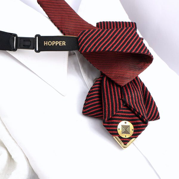 Red and black striped dog tie with a gold button and black strap labeled 'Hopper' on a white background. red black striped jabot tie, gold Gedimino stulpai emblem, handmade heritage necktie, Lithuanian cultural fashion, artisan jabot-style tie, elegant striped tie gold badge, luxury heritage necktie, cultural fashion accessory, Lithuanian identity tie, formal jabot tie, handcrafted Lithuanian motif tie