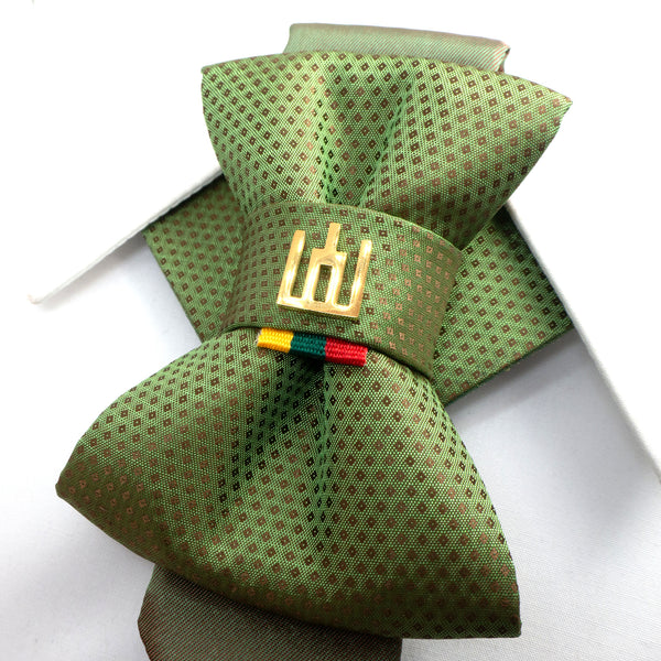 Green patterned bow tie with a decorative clasp on a white  Unique artisan necktie in green fabric, featuring Gediminas Pillars emblem and Lithuania tricolor accent, perfect gift for national pride and elegance,
Luxury handmade jabot tie in green patterned fabric, decorated with Gediminas Columns and tricolor detail, unisex accessory for weddings, concerts, formal occasions.background