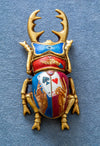 Decorative beetle with gold antlers and colorful design on a blue background