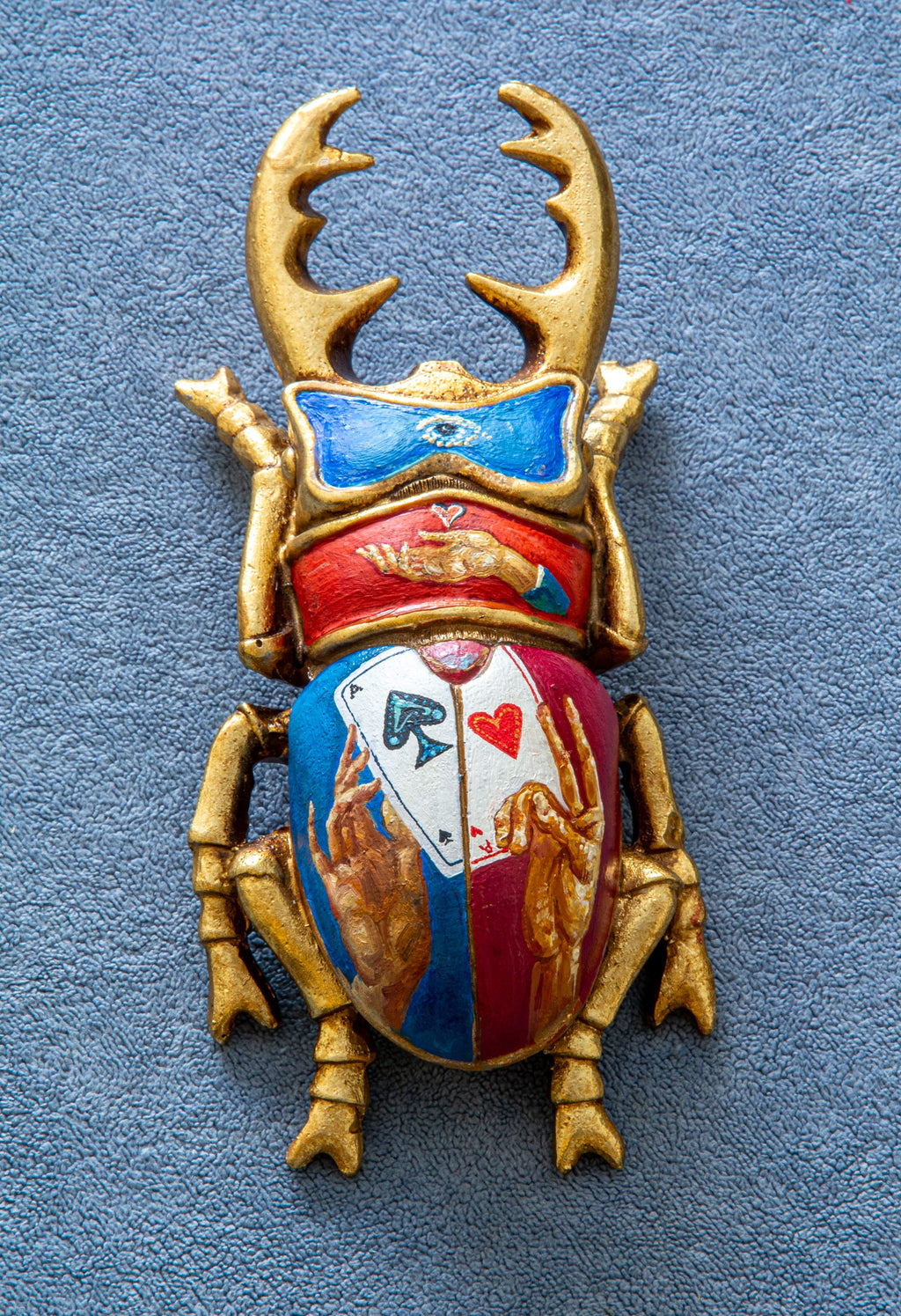 Decorative beetle with gold antlers and colorful design on a blue background