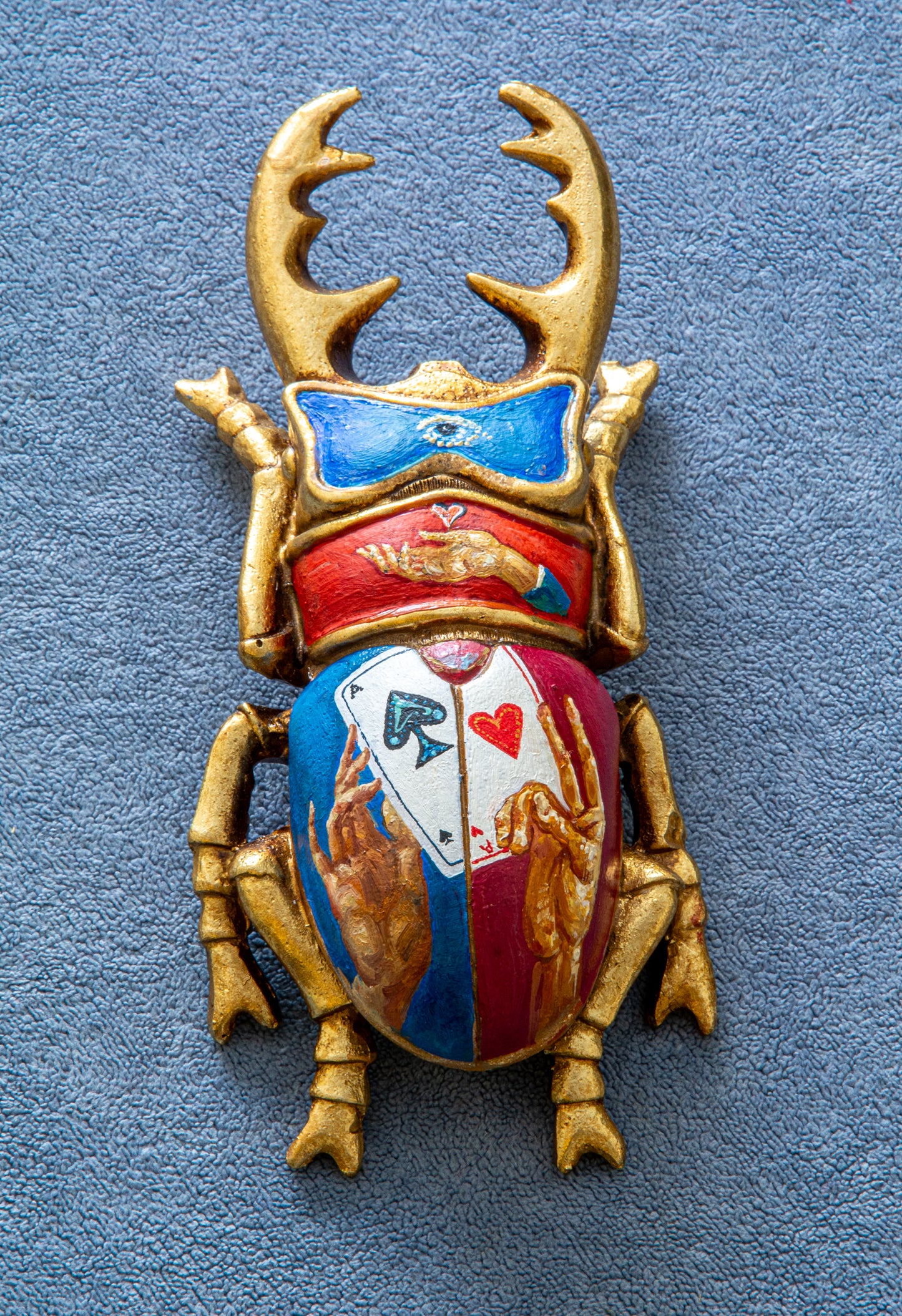 Decorative beetle with gold antlers and colorful design on a blue background