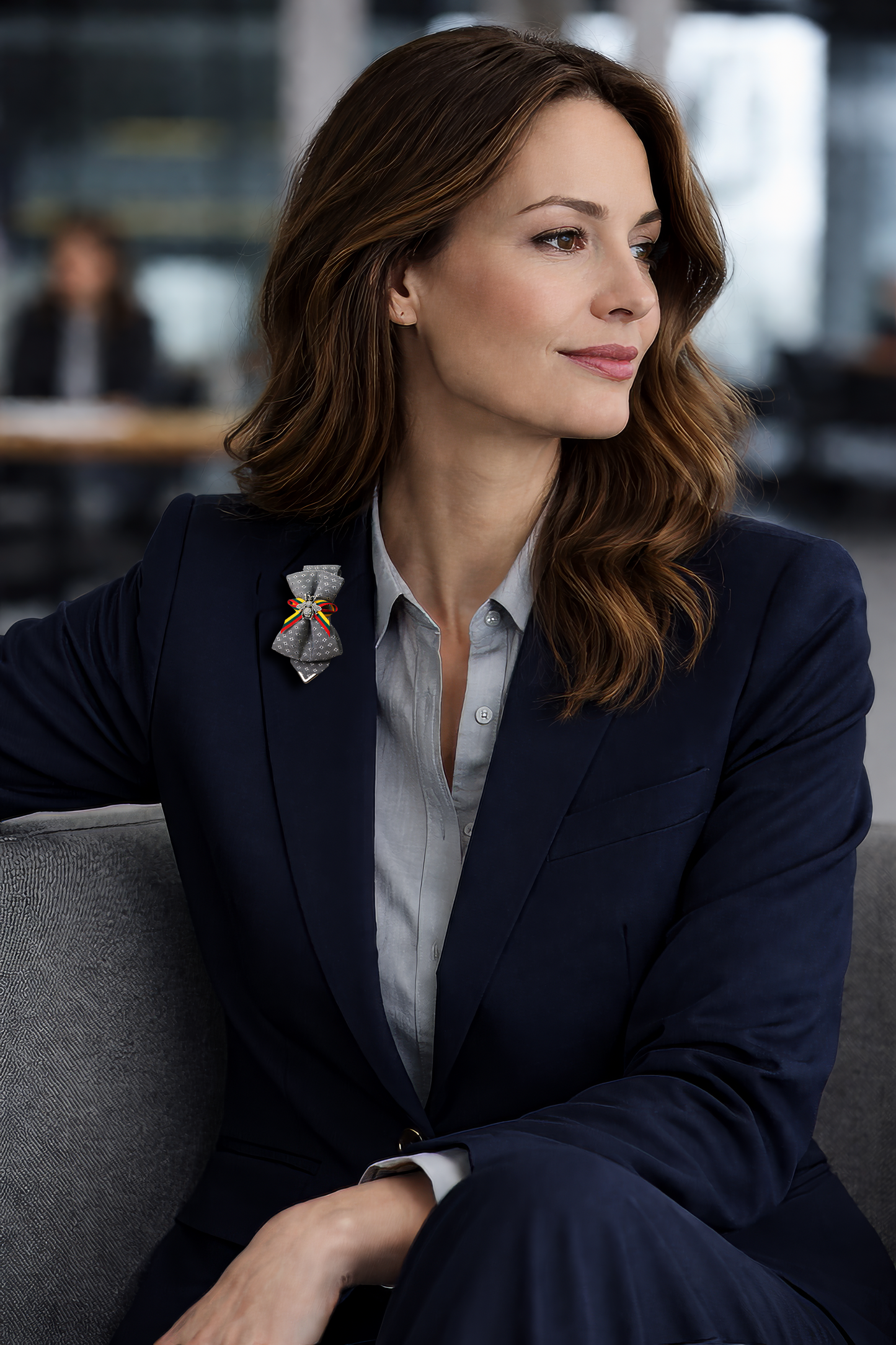 Elegant businesswoman wearing handmade bow brooch on navy blazer lapel, close up focus on artistic fabric brooch accessory, grey polka dot statement brooch with colorful ribbon detail, unique designer brooch for professional outfit, modern CEO styling luxury handcrafted lapel accessory, women office fashion with distinctive decorative brooch, sophisticated blazer look featuring artisan bow pin, contemporary corporate style enhanced with artistic brooch detail