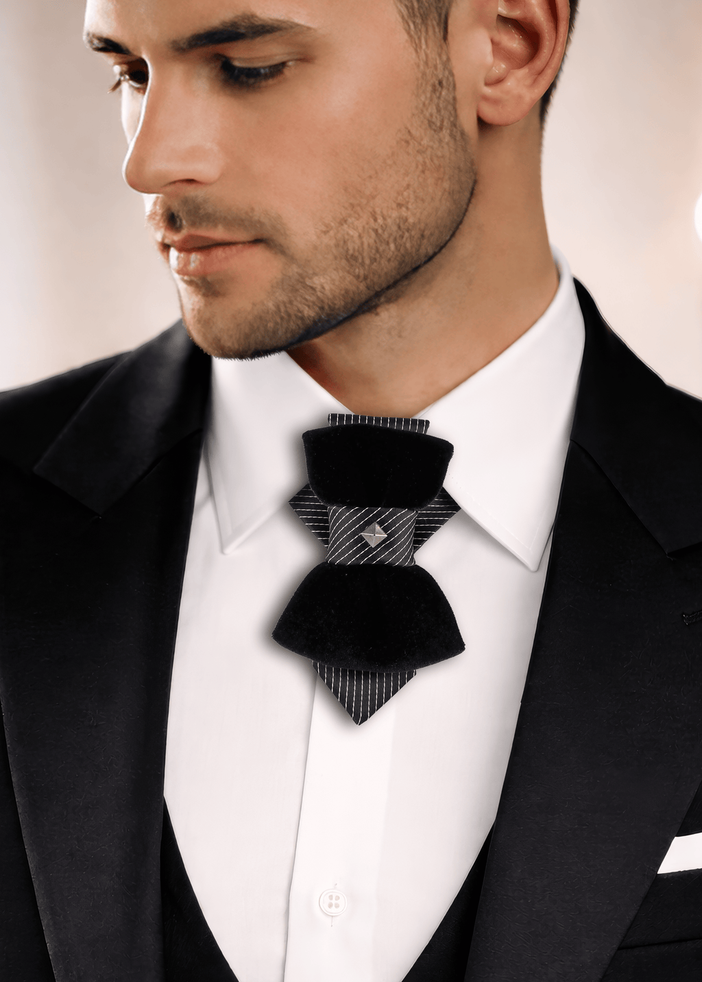 Man wearing a black bow tie with a patterned design on a blurred  lack Velvet Vertical Bow Tie “Pompea” – Designer Statement Tie for Groom, Weddings & Elegant Style
The Hopper Tie “Pompea” is an original designer piece created for those moments when ordinary style is not enough. Combining the elegance of a classic necktie with the distinctive shape of a bow tie, this vertical bow tie creates a look that is refined, artisbackground
