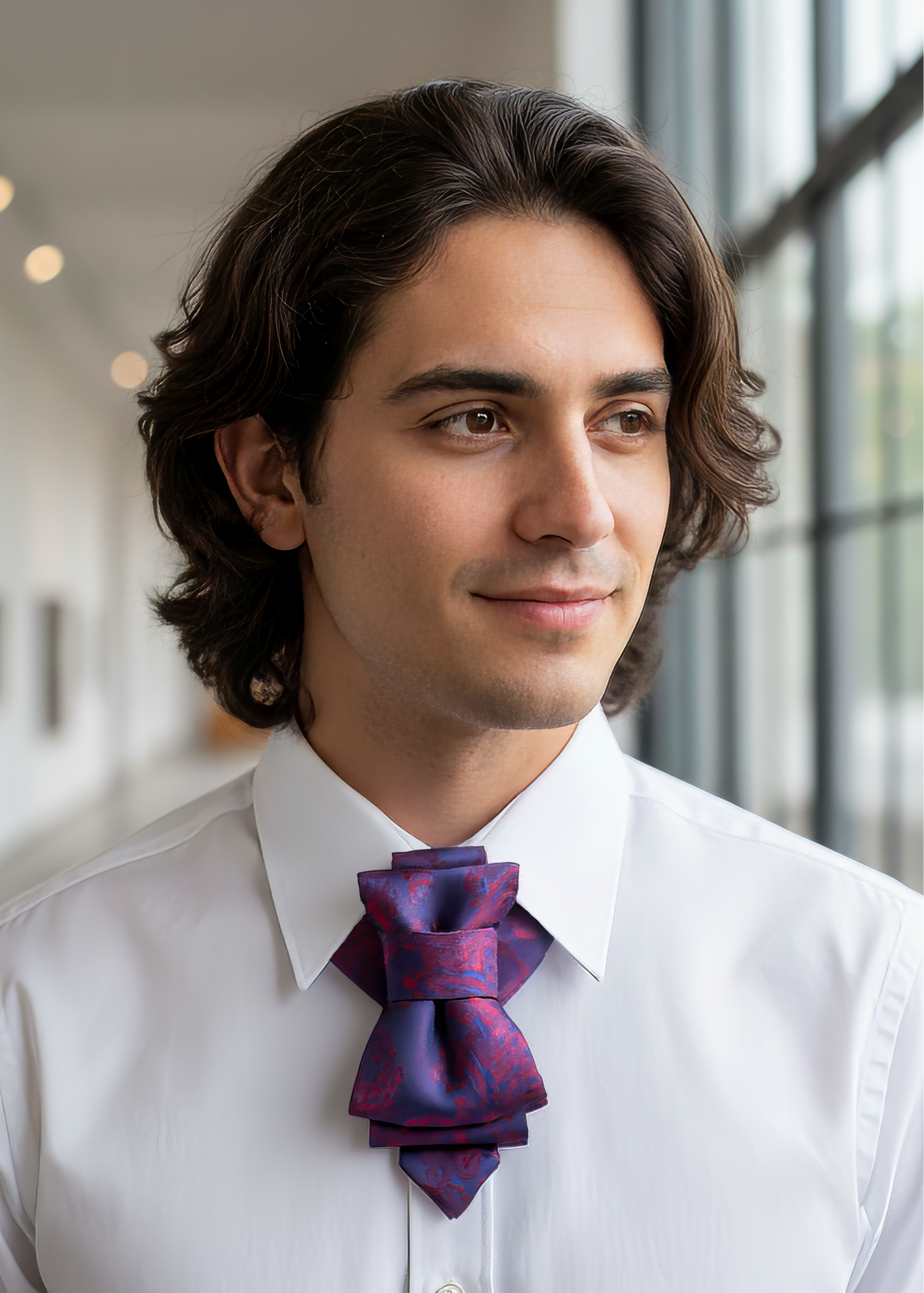 Man wearing a white shirt and purple tie with a blurred indoor background