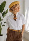 Stylish woman wearing a handmade gold bow tie with a white shirt and yellow beret