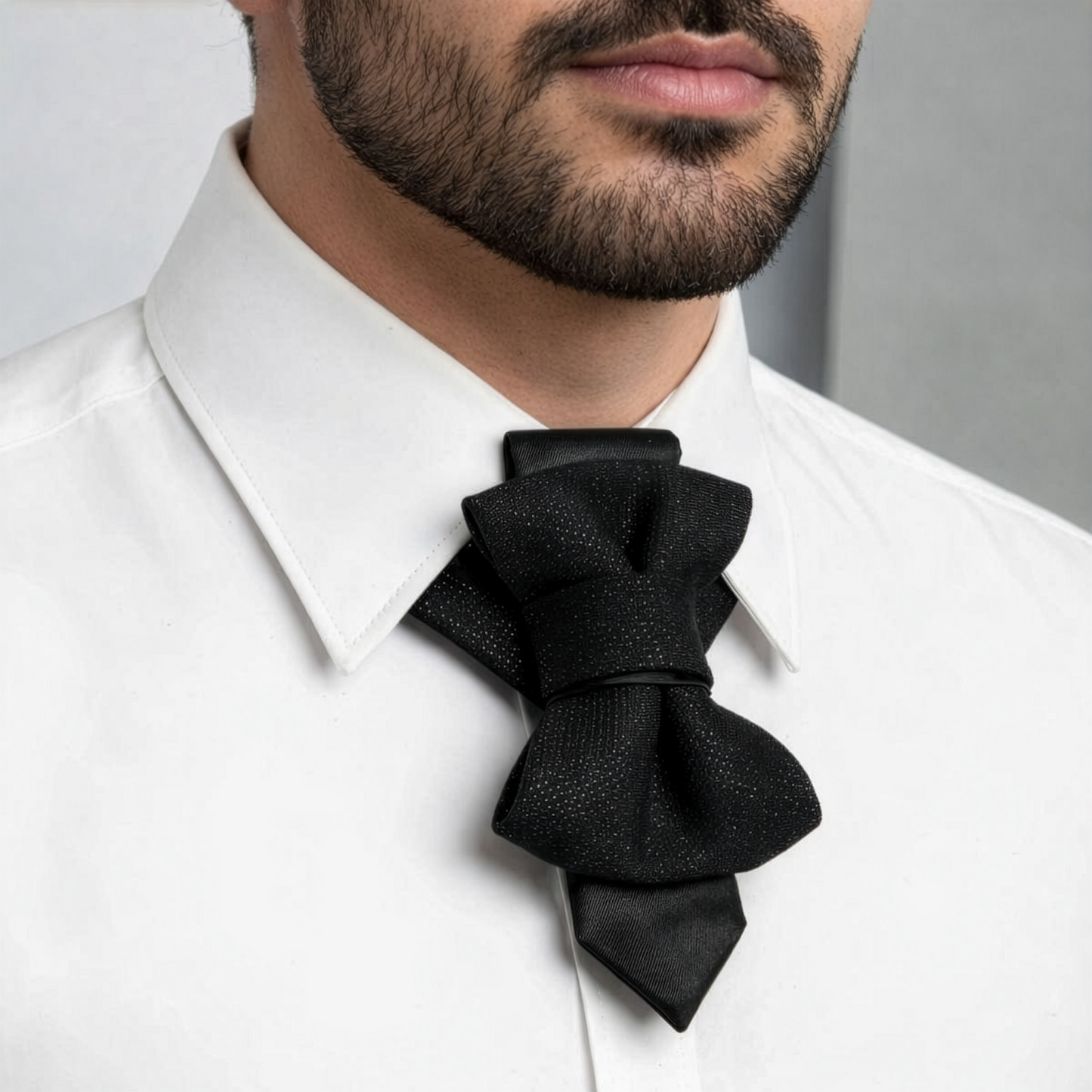 Man wearing a white shirt with a black bow tie against a neutral  Handmade black hopper tie for wedding, original designer bow tie on white shirt, Luxury black wedding hopper tie, modern bow tie and necktie hybrid, Elegant handmade hopper tie for groom, minimalist black formal accessory, Original design black hopper tie, premium wedding bow tie for men, Modern black hopper tie for formal wear, handcrafted wedding neck accessory, Designer handmade hopper tie, sophisticated black tiebackground