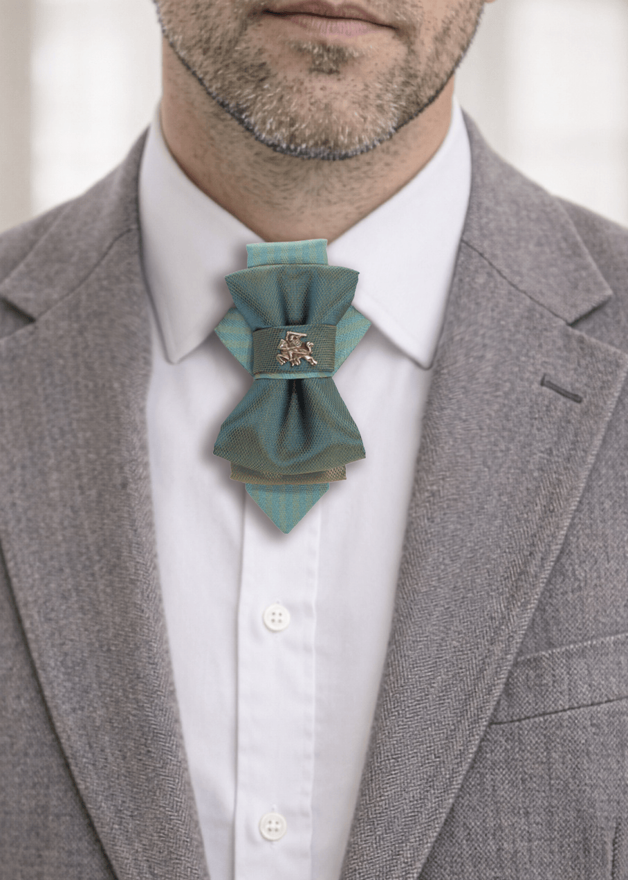 Man wearing a gray suit with a white shirt and a decorative blue bow tie handmade luxury hopper tie, 13 cm vertical bow tie necklace, unique designer neck accessory, teal and gold fabric tie with metal pin, modern unisex statement tie, artistic wedding neckwear, groom alternative tie, minimalist luxury fashion accessory, handcrafted european design neckpiece