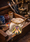 Decorative pendant on a cloth inside a wooden box with art supplies in the background one of a kind hand painted art necklace, luxury wearable art jewelry, miniature oil painting beetle pendant, handmade artist jewelry, unique statement necklace, fine art jewelry, hand painted miniature under microscope, professional artist made pendant, gold filigree necklace, collectible wearable artwork, elegant artistic necklace for everyday and special occasions