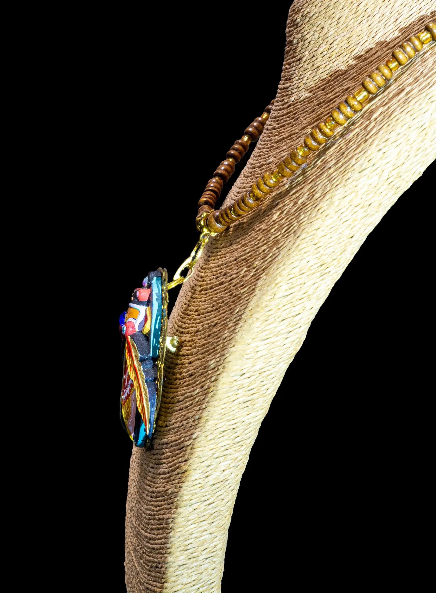 Colorful beaded necklace on a wooden stand against a black background