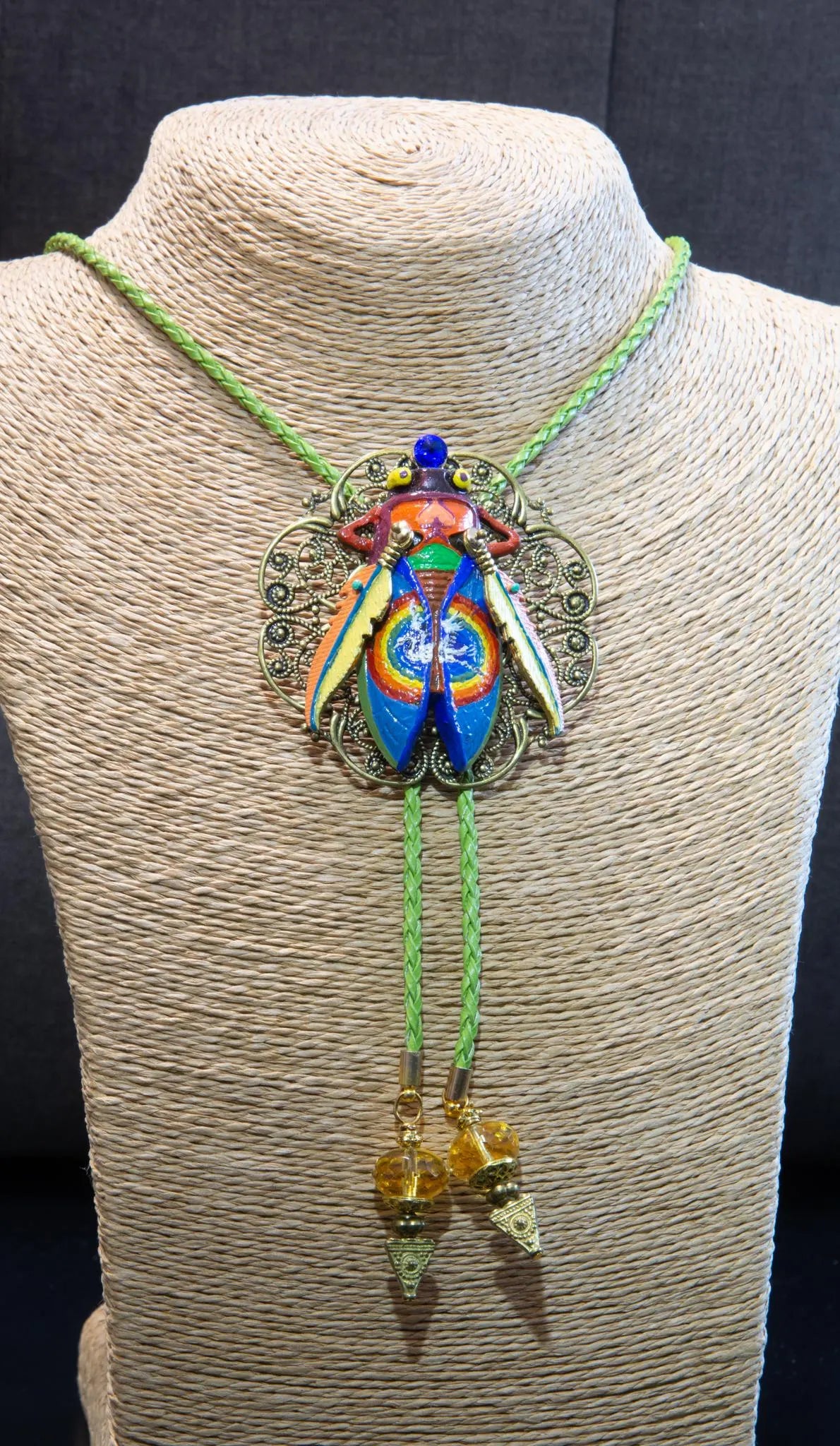 Colorful beetle-shaped pendant on a green cord displayed on a mannequin Luxury art pendant for special occasions, Sophisticated wearable art jewelry styling, Unique gift for art lover woman, Meaningful original art gift for her, Collector miniature painting jewelry piece, One of a kind handmade pendant gift idea, Artistic luxury jewelry for refined taste, Exclusive author jewelry by Marijus Piekuras