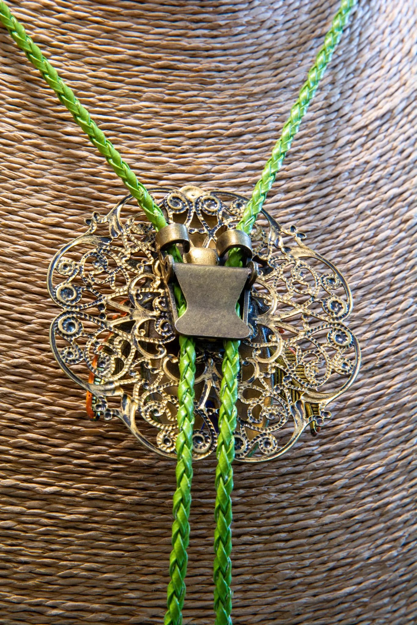 Decorative bolo tie with intricate design and green braided cord on a textured brown background Luxury art pendant for special occasions, Sophisticated wearable art jewelry styling, Unique gift for art lover woman, Meaningful original art gift for her, Collector miniature painting jewelry piece, One of a kind handmade pendant gift idea, Artistic luxury jewelry for refined taste, Exclusive author jewelry by Marijus Piekuras