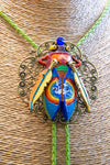 Colorful beetle-shaped pendant on a textured surface Luxury art pendant for special occasions, Sophisticated wearable art jewelry styling, Unique gift for art lover woman, Meaningful original art gift for her, Collector miniature painting jewelry piece, One of a kind handmade pendant gift idea, Artistic luxury jewelry for refined taste, Exclusive author jewelry by Marijus Piekuras