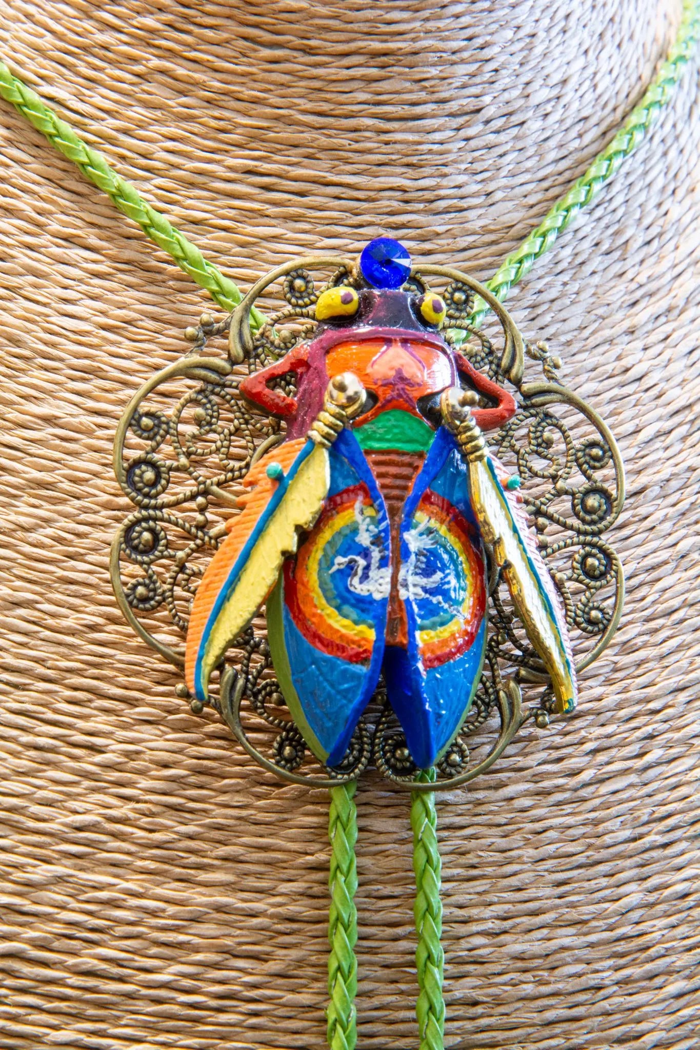 Colorful beetle-shaped pendant on a textured surface Luxury art pendant for special occasions, Sophisticated wearable art jewelry styling, Unique gift for art lover woman, Meaningful original art gift for her, Collector miniature painting jewelry piece, One of a kind handmade pendant gift idea, Artistic luxury jewelry for refined taste, Exclusive author jewelry by Marijus Piekuras