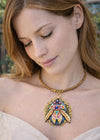 Woman wearing a decorative necklace with a large pendant outdoors one of a kind hand painted art necklace, luxury wearable art jewelry, miniature oil painting beetle pendant, handmade artist jewelry, unique statement necklace, fine art jewelry, hand painted miniature under microscope, professional artist made pendant, gold filigree necklace, collectible wearable artwork, elegant artistic necklace for everyday and special occasions