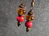 Pair of earrings with red and amber beads on a gray background