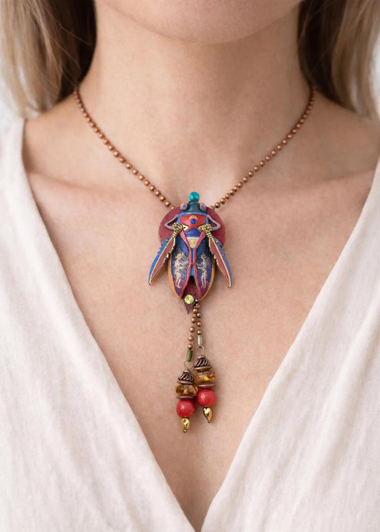 Necklace with a colorful pendant and beads worn by a person in a white top unique gift for her, art lover gift, handmade jewelry gift, collectible art necklace, luxury statement gift, anniversary gift idea, birthday gift for wife, gift for creative woman, meaningful artistic jewelry, museum style pendant gift, renaissance inspired necklace, fantasy insect jewelry, heirloom style accessory, artisan designer necklace, special occasion jewelry, romantic gift idea, Christmas gift for her, Valentine gift jewelry