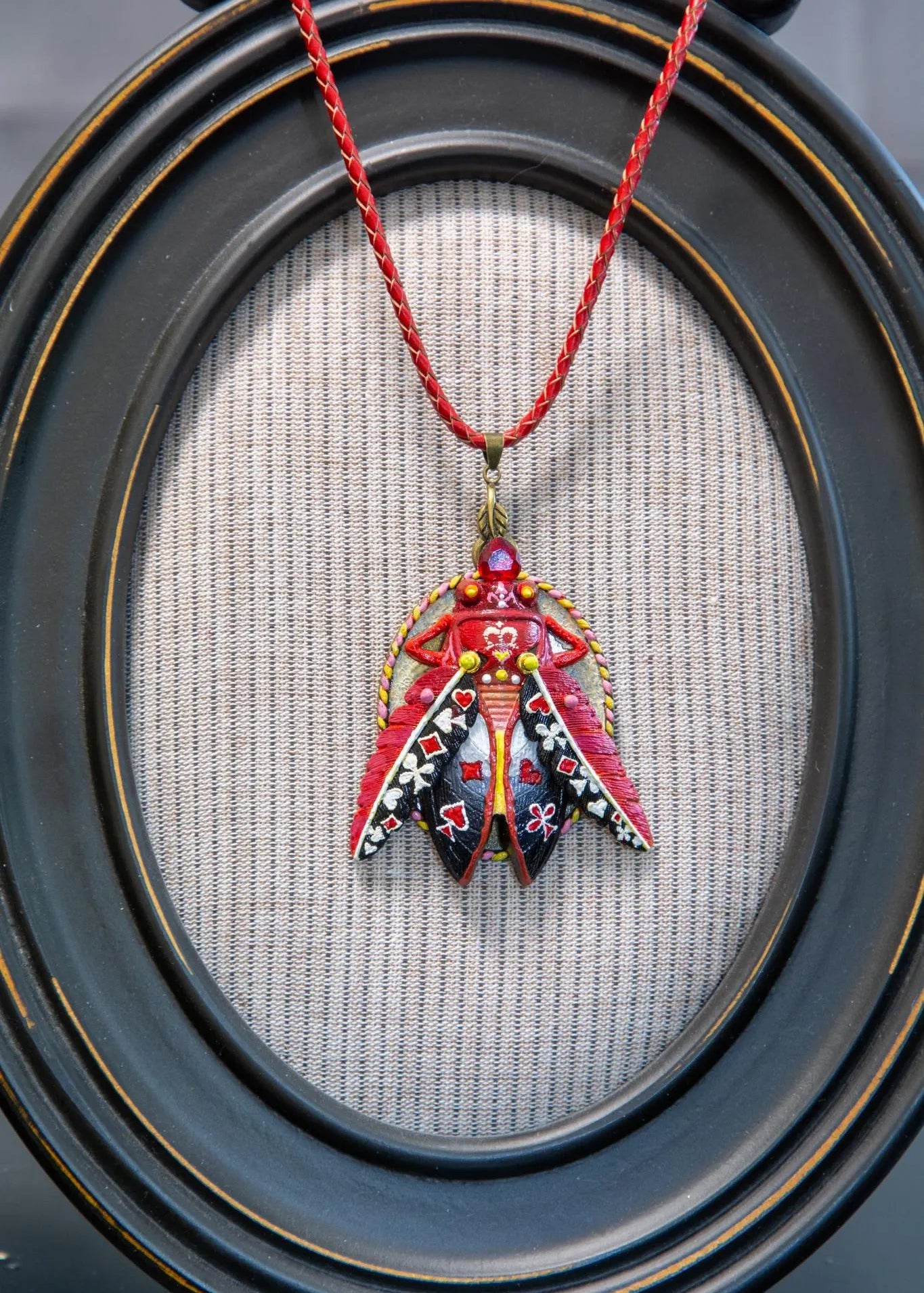 Decorative pendant on a red string against a textured fabric background