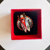 Heart-shaped jewelry with butterfly design in a red box on a white surface