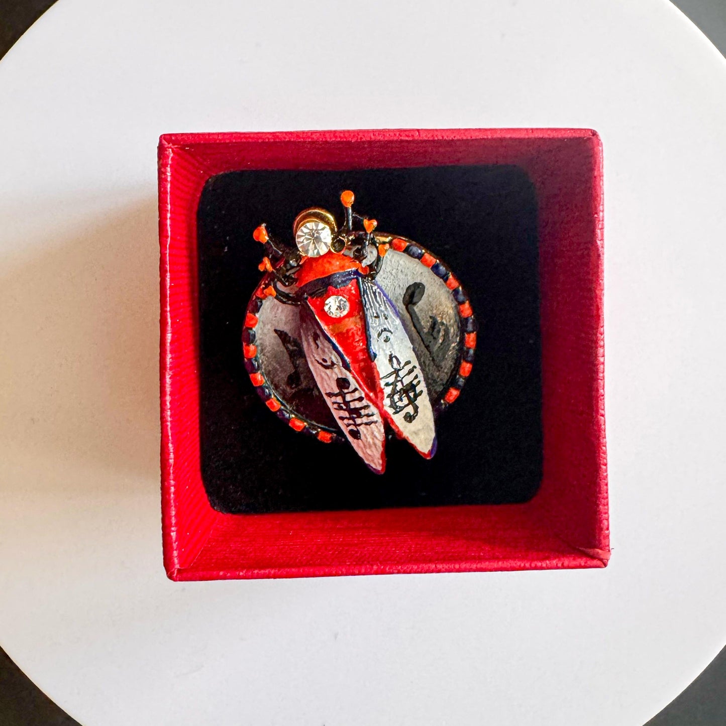 Heart-shaped jewelry with butterfly design in a red box on a white surface