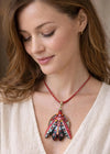 Woman wearing a red beaded necklace with a decorative pendant hand painted scarab necklace red black pendant, statement insect neck accessory, unique artist jewelry for women, bold red cord pendant necklace, wearable art beetle pendant, handmade enamel scarab charm, artistic fashion necklace close up, one of a kind insect jewelry, luxury artisan pendant for art lover, red gemstone scarab necklace, contemporary statement neckpiece, collectible art jewelry pendant, designer handmade insect necklace