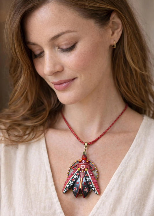 Woman wearing a red beaded necklace with a decorative pendant hand painted scarab necklace red black pendant, statement insect neck accessory, unique artist jewelry for women, bold red cord pendant necklace, wearable art beetle pendant, handmade enamel scarab charm, artistic fashion necklace close up, one of a kind insect jewelry, luxury artisan pendant for art lover, red gemstone scarab necklace, contemporary statement neckpiece, collectible art jewelry pendant, designer handmade insect necklace