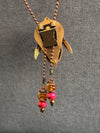 Decorative necklace with gold pendant and red beads on a gray background
