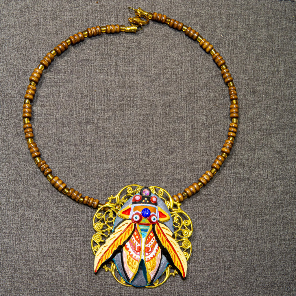 Necklace with decorative pendant on a gray background one of a kind hand painted art necklace, luxury wearable art jewelry, miniature oil painting beetle pendant, handmade artist jewelry, unique statement necklace, fine art jewelry, hand painted miniature under microscope, professional artist made pendant, gold filigree necklace, collectible wearable artwork, elegant artistic necklace for everyday and special occasions