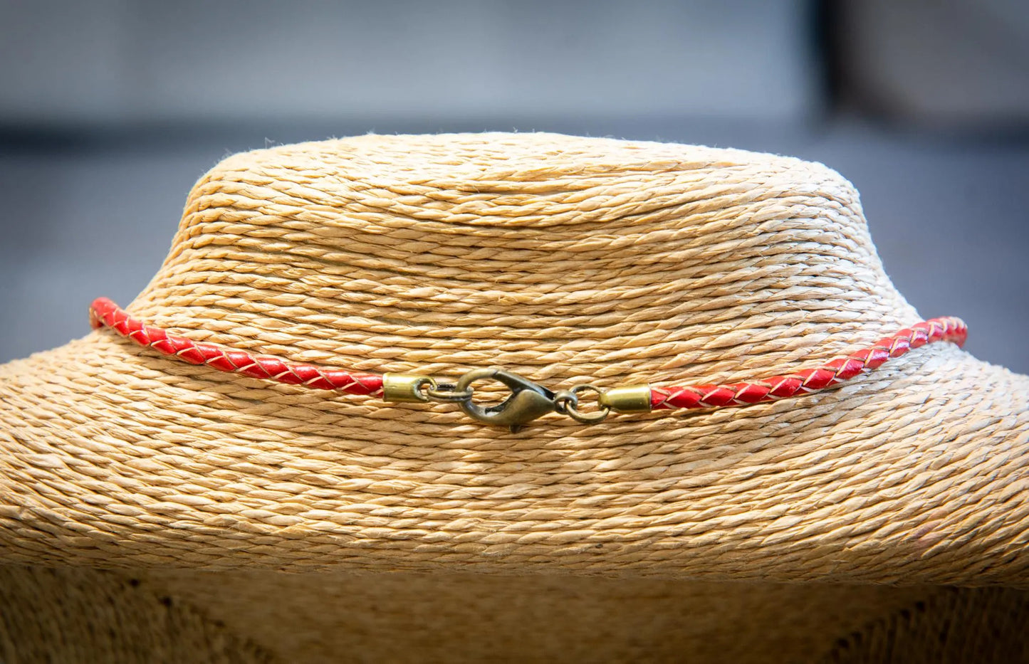 Close-up of a straw hat with a red and gold ribbon on a blurred background