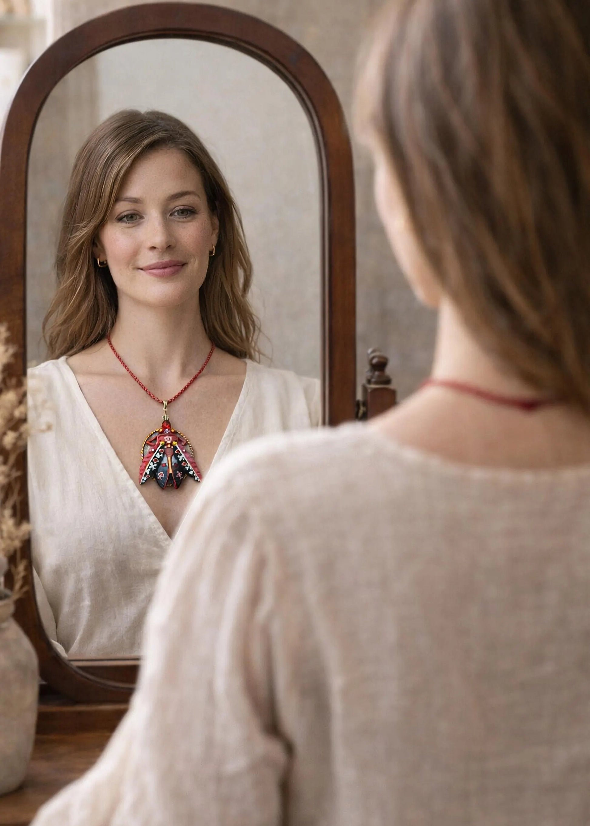 Woman looking at herself in a mirror wearing a necklace with a pendant hand painted scarab necklace red black pendant, statement insect neck accessory, unique artist jewelry for women, bold red cord pendant necklace, wearable art beetle pendant, handmade enamel scarab charm, artistic fashion necklace close up, one of a kind insect jewelry, luxury artisan pendant for art lover, red gemstone scarab necklace, contemporary statement neckpiece, collectible art jewelry pendant, designer handmade insect necklace