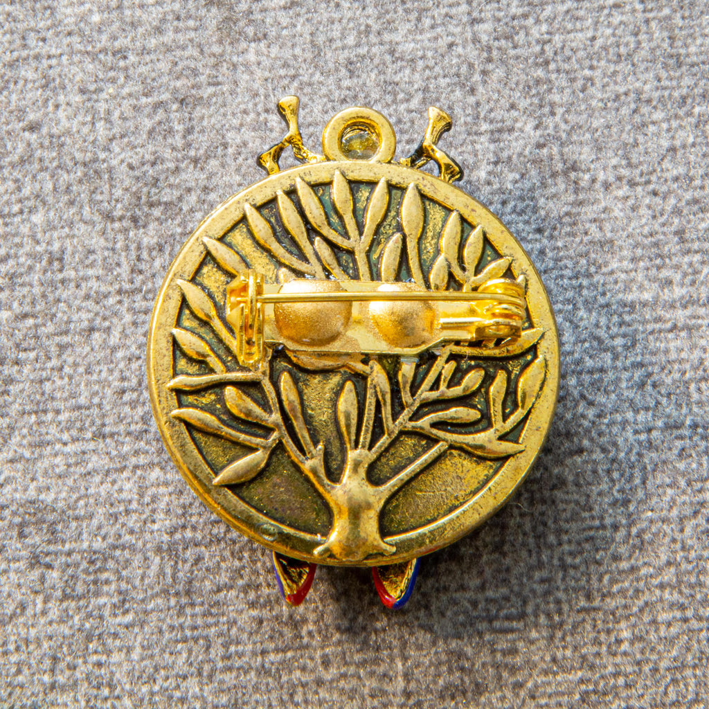 Gold-colored decorative emblem with intricate design on a textured gray background