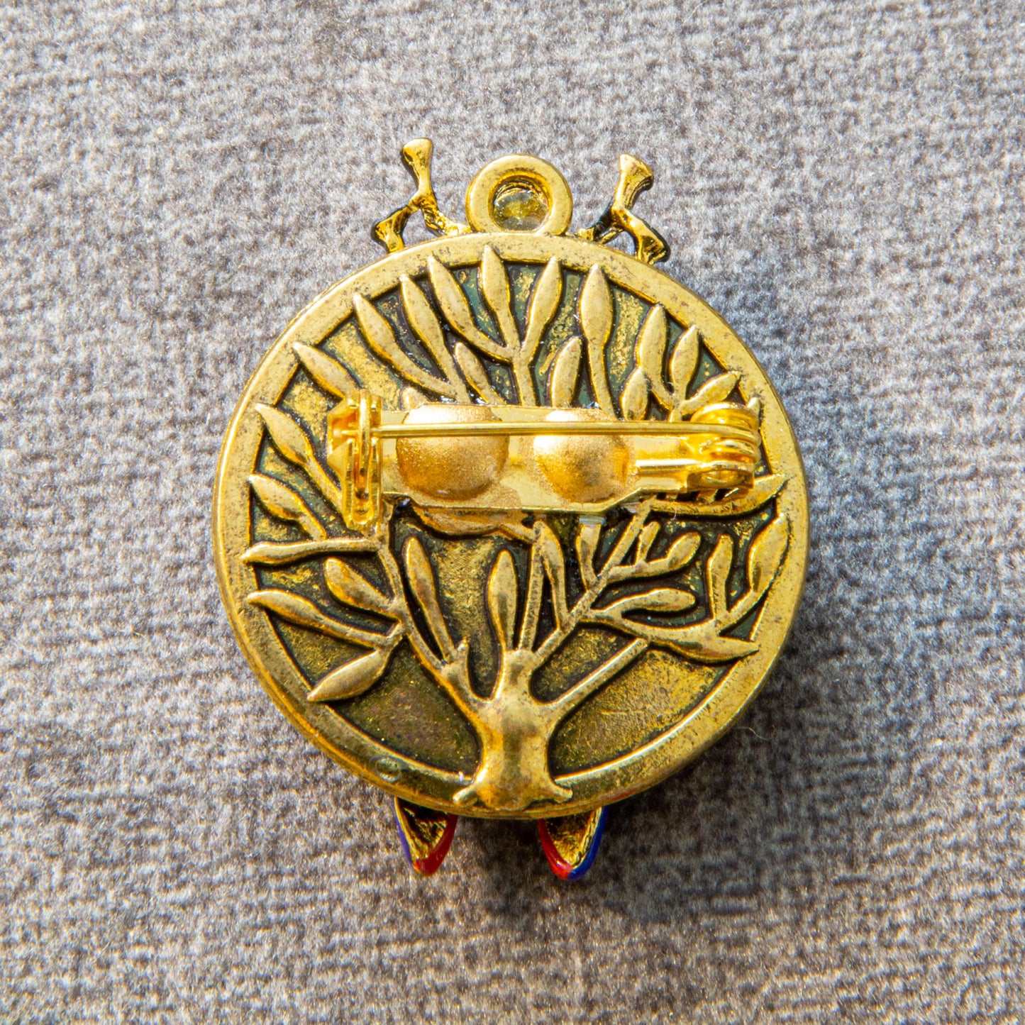 Gold-colored decorative emblem with intricate design on a textured gray background
