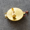 Gold brooch with intricate design on a gray background