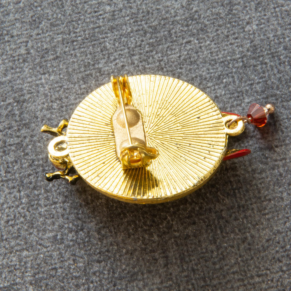 Gold brooch with intricate design on a gray background