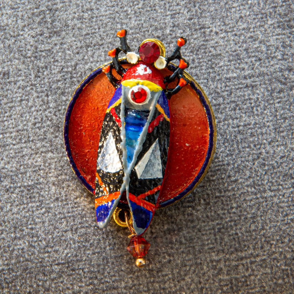 Colorful brooch with butterfly design on a textured gray background