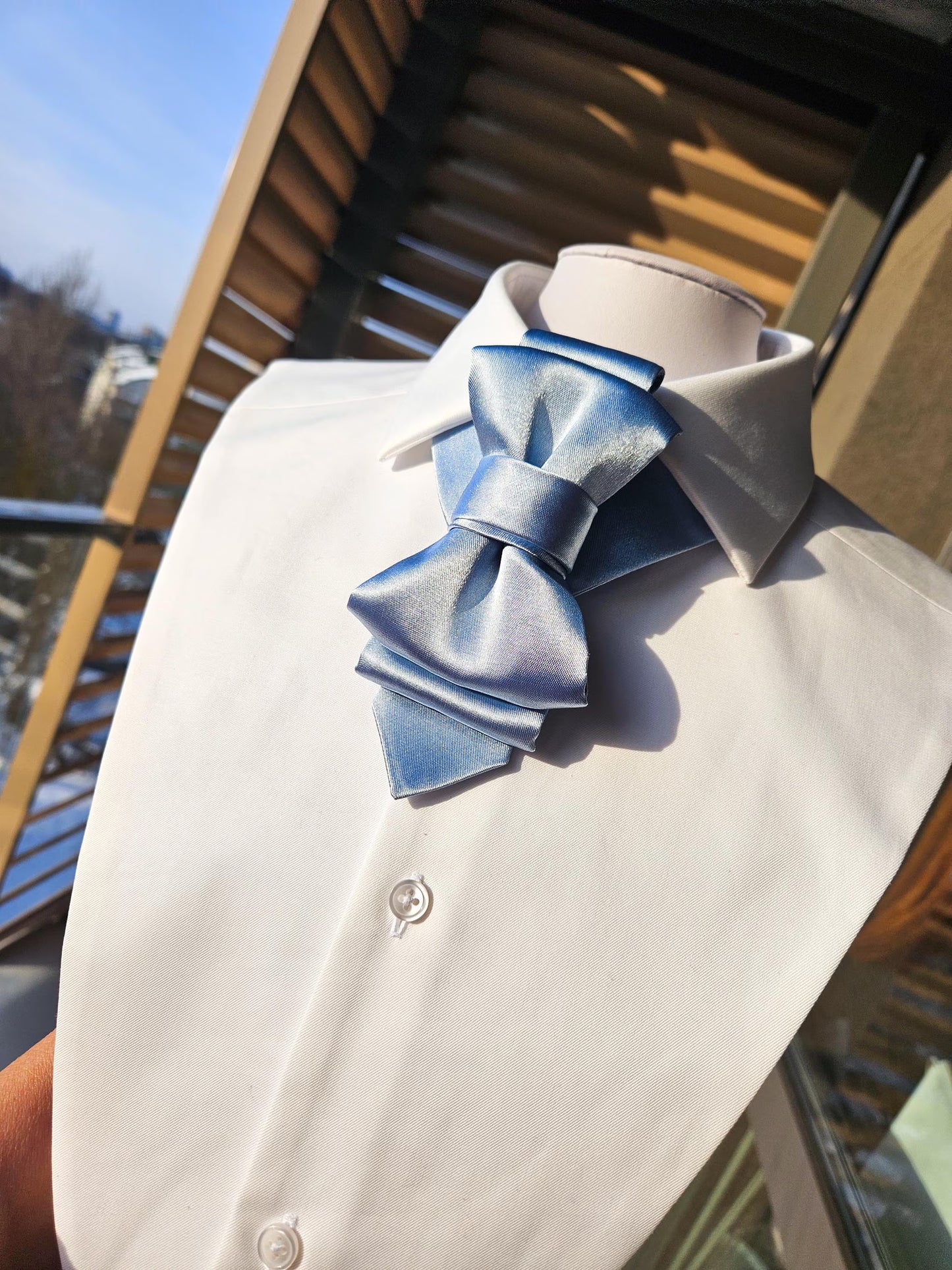 White shirt with a large blue bow tie on a wooden surface ice blue bow tie women, vertical bow tie, satin bow tie light blue, glacier blue necktie, women statement tie, unisex bow tie, modern bow tie design, sculptural neckwear, elegant women neck accessory, minimalist fashion accessory, wedding guest bow tie, light blue formal tie, unique designer bow tie, artistic neckwear piece, premium satin bow tie, women formal outfit accessory, stylish office outfit women, contemporary fashion tie, handmade statement