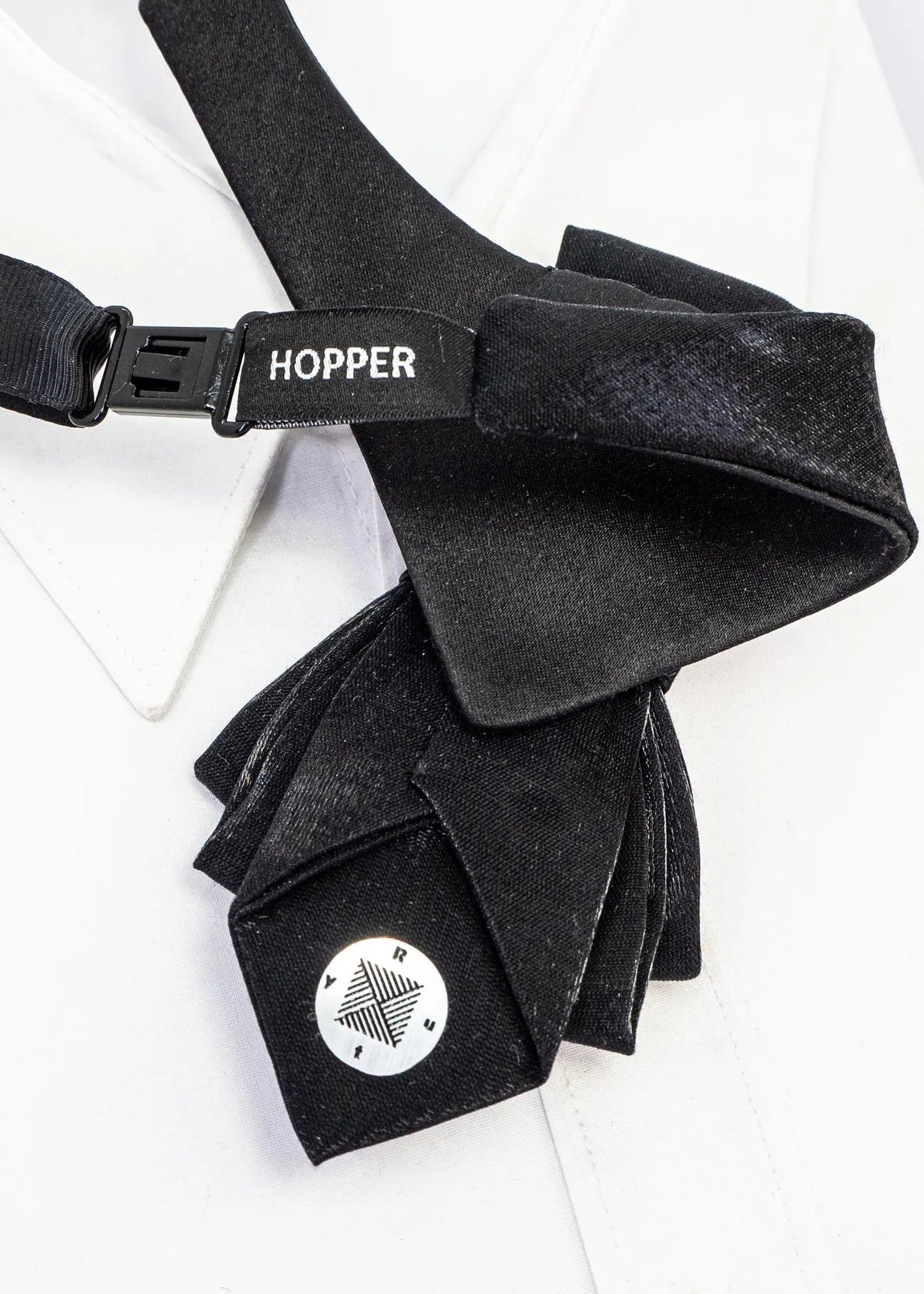 Black bow tie with 'Hopper' branding on a white background black statement tie for men, sculptural bow tie alternative, unique formal neckwear, artistic groom tie, modern wedding tie, luxury handmade necktie, sophisticated men fashion, elegant men accessory, designer neckwear piece, standout wedding look, contemporary cravat style tie, tailored suit accessory, refined black necktie, avant garde tie, formal event accessory, minimalist black tie, premium fabric tie, stylish groom outfit detail