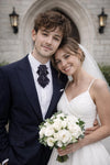 Man and woman in wedding attire standing in front of a stone archway black statement tie for men, sculptural bow tie alternative, unique formal neckwear, artistic groom tie, modern wedding tie, luxury handmade necktie, sophisticated men fashion, elegant men accessory, designer neckwear piece, standout wedding look, contemporary cravat style tie, tailored suit accessory, refined black necktie, avant garde tie, formal event accessory, minimalist black tie, premium fabric tie, stylish groom outfit detail